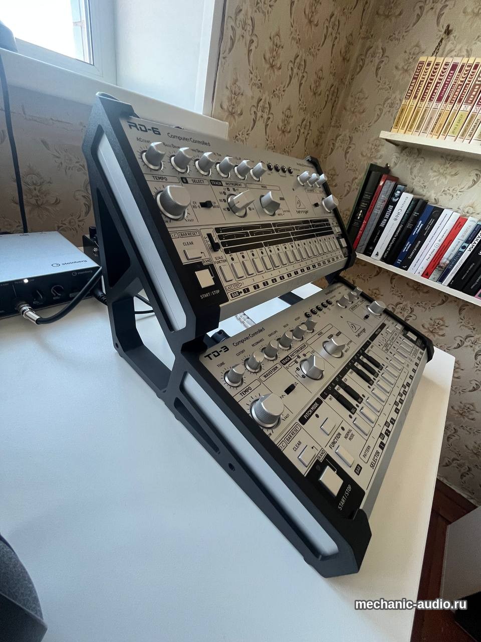 Аналоговая драм-машина Behringer RD-6 на двухъярусной подставке над басовым синтезатором Behringer TD-3, рядом аудиоинтерфейс Steinberg