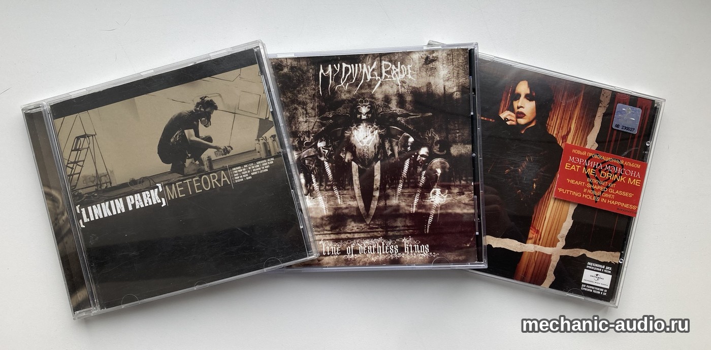 Три компакт-диска веером на светлом столе: Linkin Park «Meteora», My Dying Bride «A Line of Deathless Kings» и Marilyn Manson «Eat Me, Drink Me» с красной наклейкой